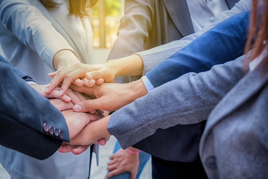 Young businessmen join hands together to conduct business together for unity as a team.