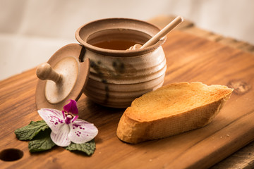 Obraz na płótnie Canvas Honey Dripping Onto Toast With Pot and Honey Stick