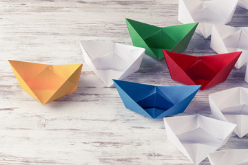 Business leadership concept with white and color paper boats on 