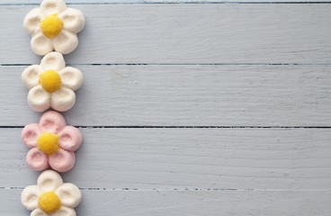 Border of daisy marshmallow sweets on duck egg blue painted table 