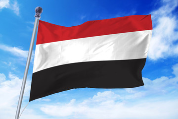 Flag of Yemen developing against a clear blue sky