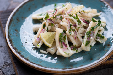 Salad with boiled calamari with onion and parsley filling, close-up, selective focus