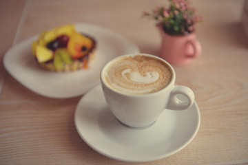 Cappuccino coffee on a wooden table with cake