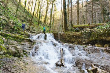 Tourists in a mountain gorge wading through a small river in the vicinity of the town of Goryachiy Klyuch