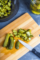 Cucumbers or pickled gherkins with a knife on a wooden cutting board. Blue gray background. Bank with cucumbers.