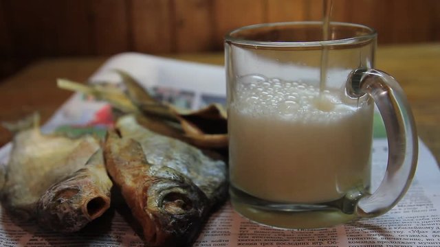 Beer and dried fish on a wooden table.
