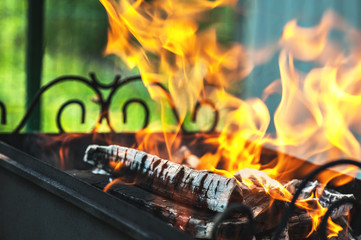 burning wood in a metal barbecue with smoke and embers diagonally on a bright green background, horizontal frame