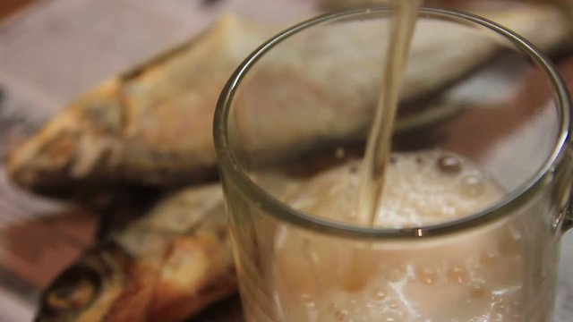 Beer and dried fish on a wooden table.