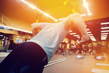 close-up man is engaged with a  fitness straps of athletes in the gym. concept of fitness. high...