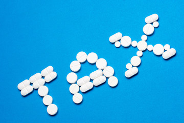 Word TAX made of white pills on blue background