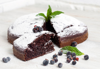 Sliced chocolate pie with mint and ingredients on table. Chocolate pie on wooden table. Vegan cake