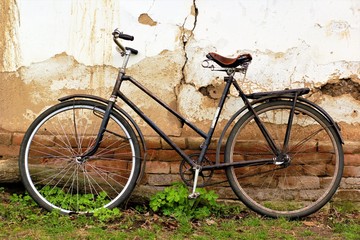 Old vintage rusty bike against the cracked wall