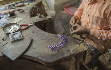 Indian Jeweler making an Oriental Jewelry in workshop. Handmade traditional jewel Manufacturing in Jaipur