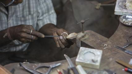 Indian Jeweler making an Oriental Jewelry in workshop. Handmade traditional jewel Manufacturing in Jaipur