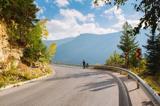 A man stands next to a Bicycle on the mountain road. Summer in the mountains of Bulgaria