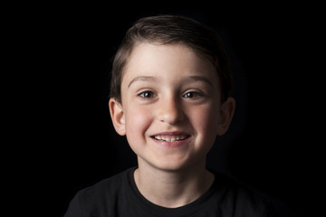 Low key portrait of young boy isolated on black background. Plenty of space left for copy. for Flyers, posters and other commercial purposes