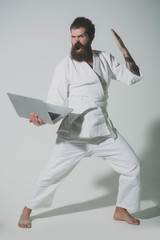 bearded shouting karate man in kimono with laptop