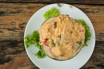 The tradition Thai steamed curry sea food in coconut on wooden background