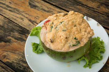 The tradition Thai steamed curry sea food in coconut on wooden background