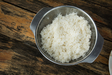 Cooked rice in pot on wooden table (wooden background)