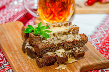 Hot snack for beer.  Roasted brown whole wheat bread with melted cheese and parsley on a wooden board.