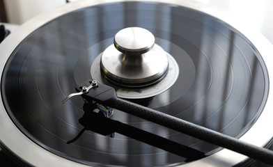 Tonearm of vintage turntable with LP record close up view