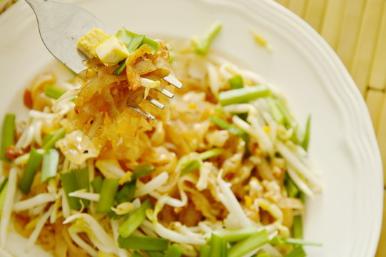 Pad Thai stir fried thin rice noodles with egg and tofu on fork