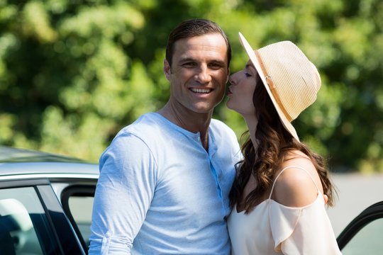 Young Woman Kissing Man By Car