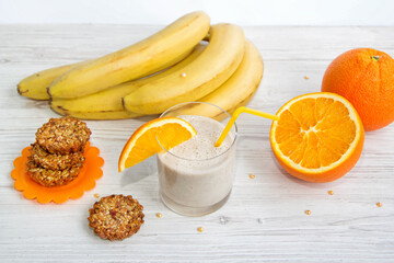 Healthy breakfast. Banana smoothie with orange slice on a glass, fruits and cookies made of sunflower seeds, sesame and honey