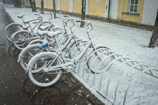 Bicycles smoothly covered with fresh snow after weather phenomena - snowfall in late April near Moscow