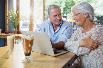 Senior couple interacting while using laptop - Powered by Adobe