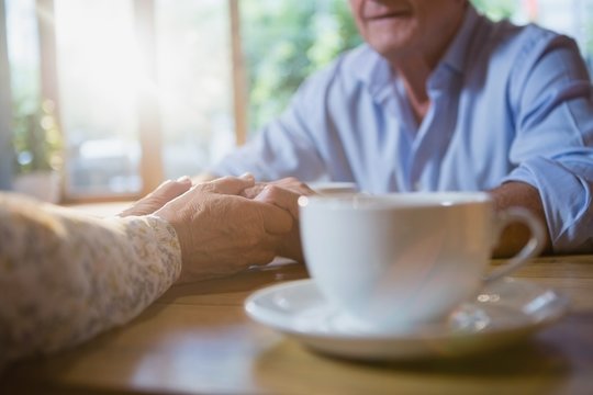Senior couple holding hands while having coffee