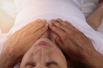 Attractive young woman having reiki healing treatment , alternative medicine concept.