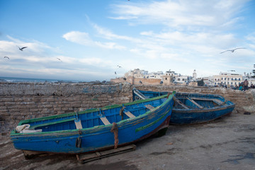 Fototapeta na wymiar MOROCCO, ESSAOUIRA - January 09, 2013. Fishing blue boats in port of Essaouira harbour with fishmens.