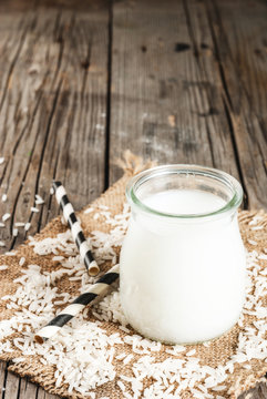 Rice milk, with rice grains. On a rustic wooden table. With a striped tube for drinking. Copy space