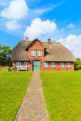 Fototapeta na wymiar Typical red brick Frisian house with thatched roof on Sylt island in List village, Germany