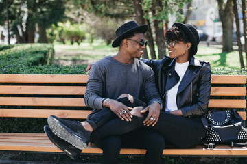 A beautiful and stylish young african couple in sunglasses and hats walking on a outdoor of summer.