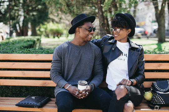 A beautiful and stylish young african couple in sunglasses and hats walking on a outdoor of summer.
