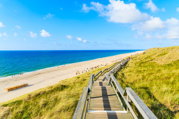 Wooden walkway along a coast of North Sea and view of beautiful beach near Wenningstedt village, Sylt island, Germany