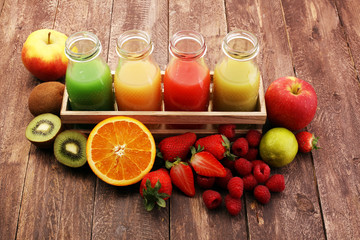 several bottles with fruit and berry juices smoothies and milkshakes , vintage wooden background, selective focus