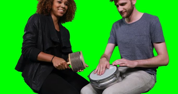 Happy mixed-race musicians playing cabasa and drum