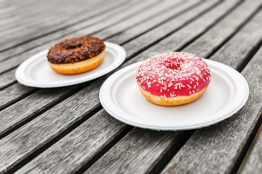 two delicious chocolate and pink donuts on wooden background