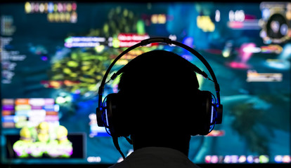 Young gamer playing video game wearing headphone.