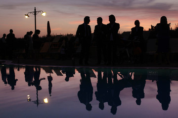 persone in silhouette durante un parti al tramonto si riflettono in una piscina