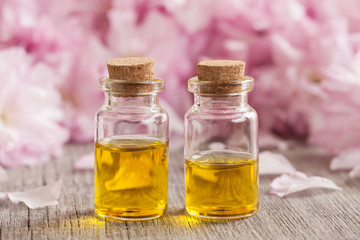 Two bottles of essential oil with pink cherry blossoms in the background
