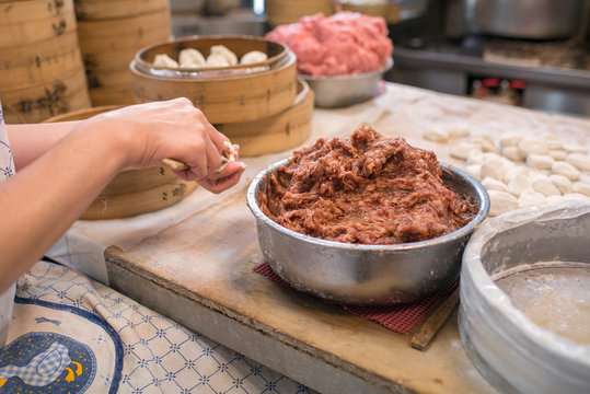 Woman making Chinese steamed meat buns in kitchen