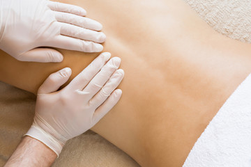 Therapist hands in protective gloves massaging man's back.