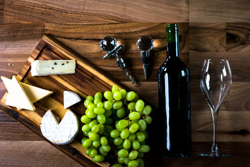 Obraz premium Wine bottles with grapes and cheese on wooden rustic background. copy space