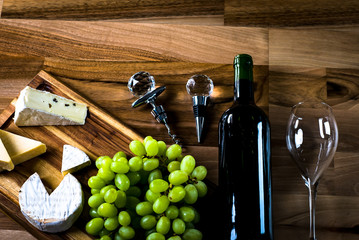 Obraz premium Wine bottles with grapes and cheese on wooden rustic background. copy space