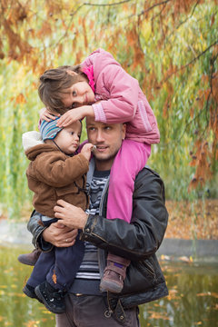 Father carrying son and daughter piggybacks